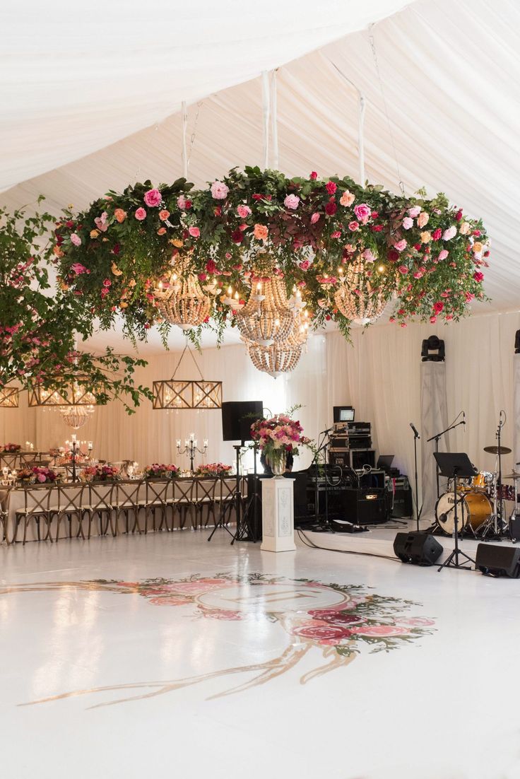 a wedding reception setup with chandelier and floral centerpieces on the dance floor