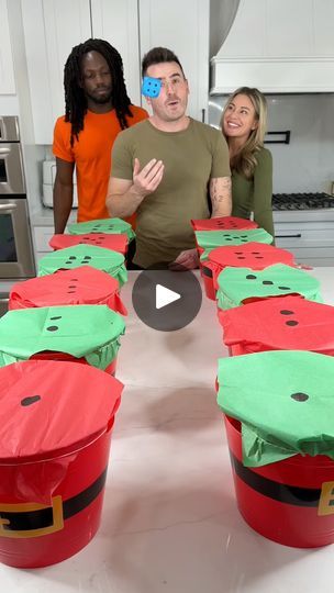 three people standing around a table covered in red and green plastic buckets with watermelon faces on them