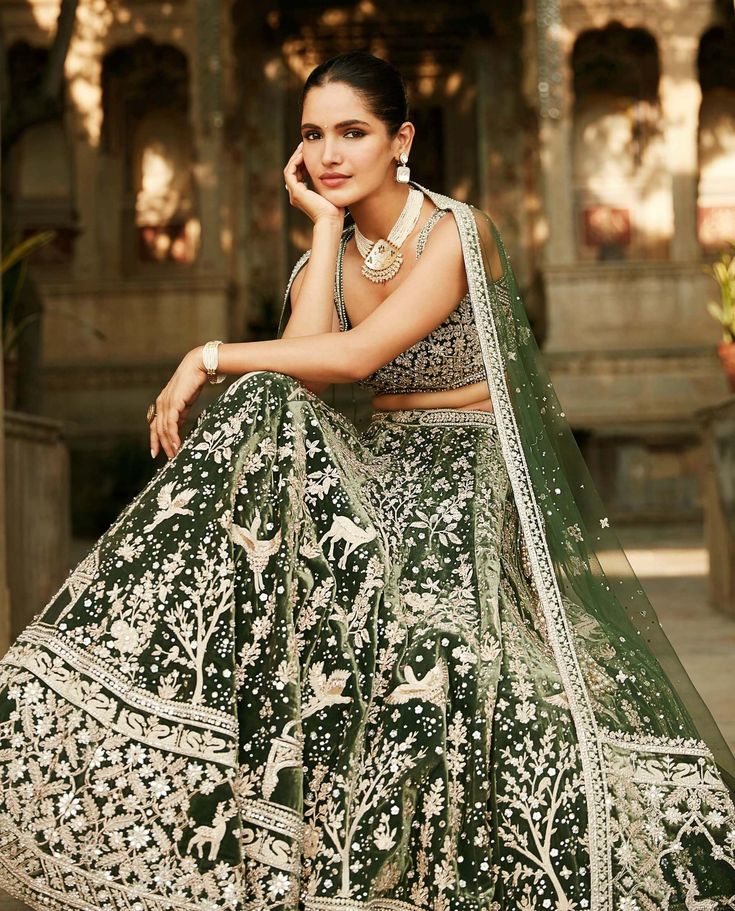 Editor's Note Reviving The Forest Green Invented Back In 2017, This Lehenga Captures The True Masai Wilderness. Young, Wild & Free. The Night Sky, The Antelopes & Cranes Created With Suchi Dori, Zardozi & Little Jaipuri Mirrors. Dupatta Panelled With An Antelope. An Eternal Statement Of Elegance. Color: Green Fabric: Velvet Components: Lehenga, Blouse & Dupatta Disclaimer: Product colour may slightly vary due to photographic lighting sources Care: Dry Clean Only About the Designer Matsya by Utka Green Lehenga Bridal, Desi Dress, Velvet Lehenga, Young Wild Free, Green Lehenga, Indian Saree Blouses Designs, Masai Mara, Wild Free, Wedding Lehenga