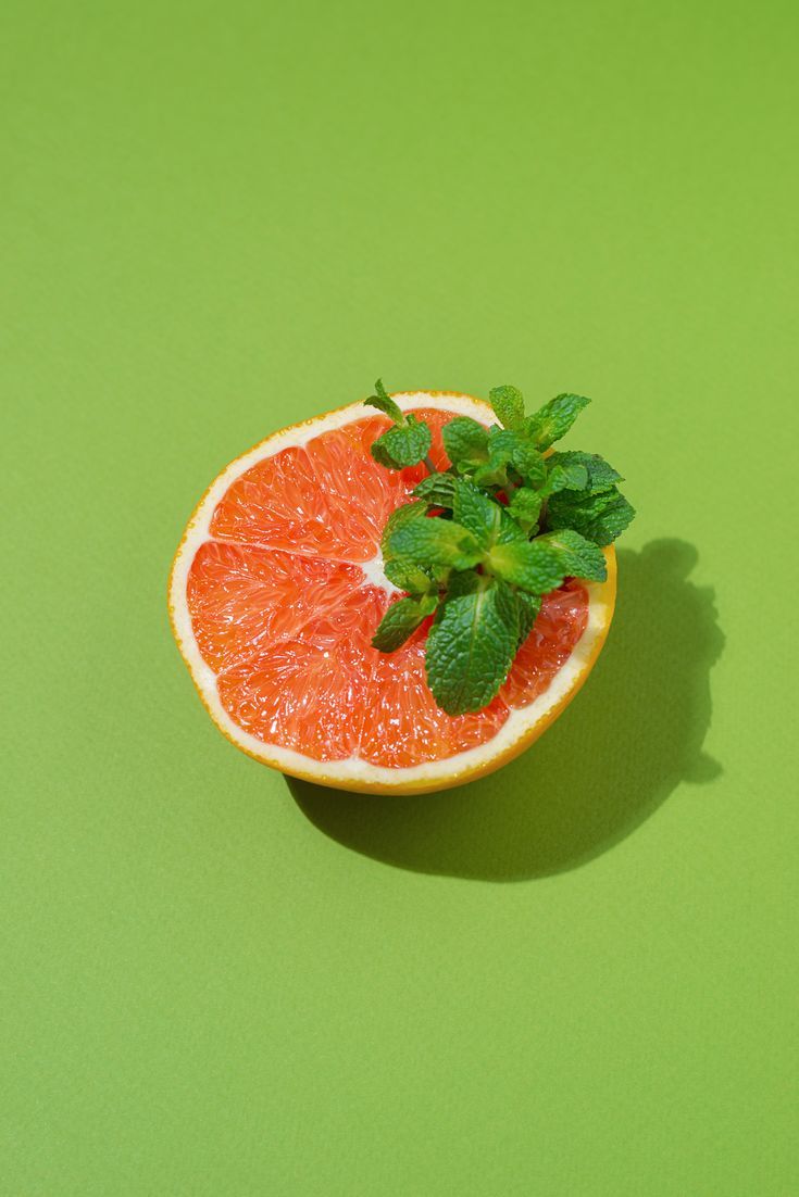 a grapefruit cut in half on a green surface