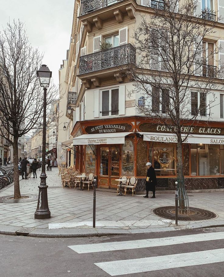 people are walking on the sidewalk in front of an old building with many windows and balconies