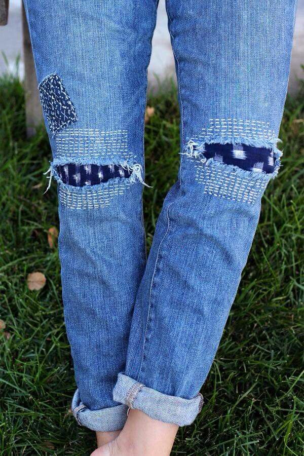 a person standing in the grass wearing blue jeans and white shoes with holes on them