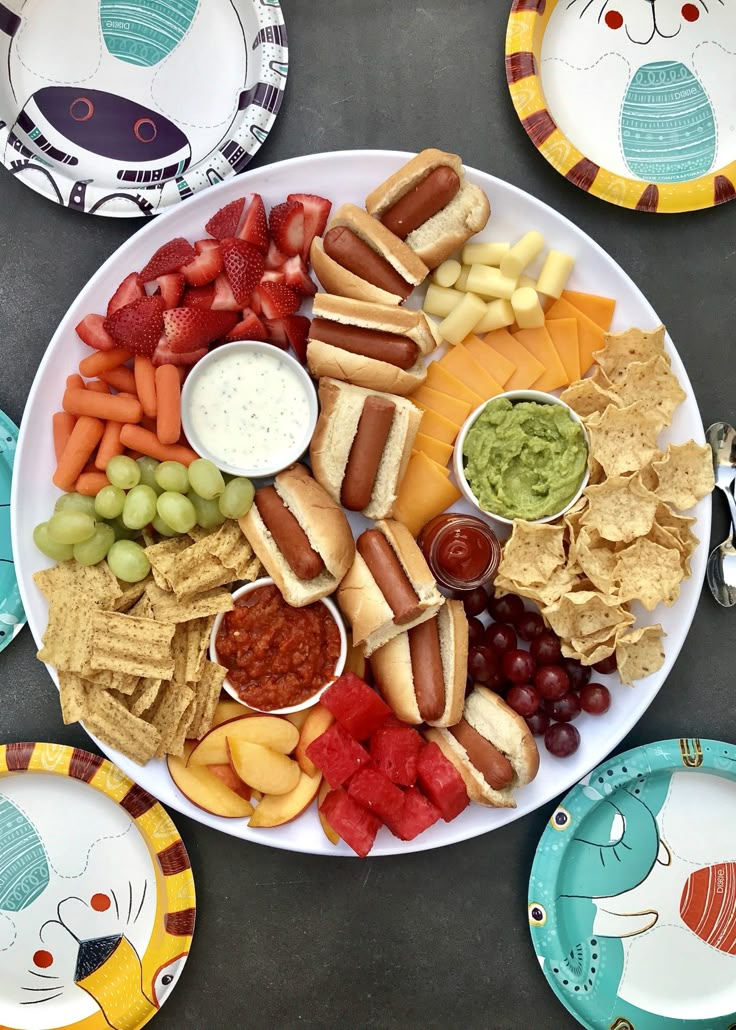 a plate full of food with chips, fruit, and dips on the side