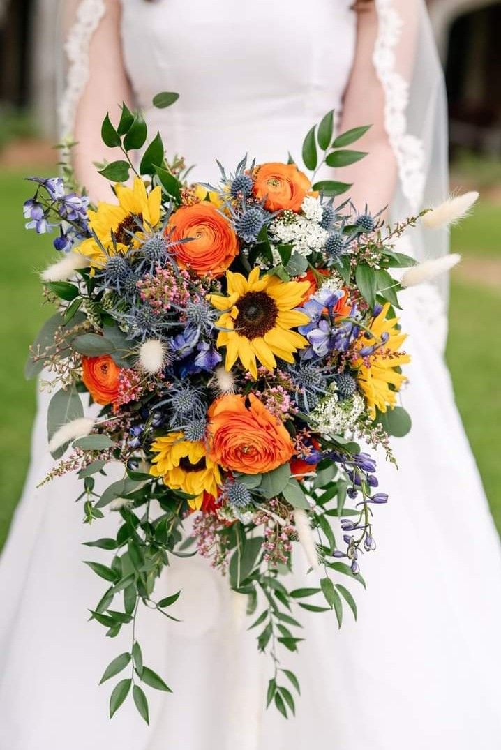 a bride holding a bouquet of sunflowers and other flowers