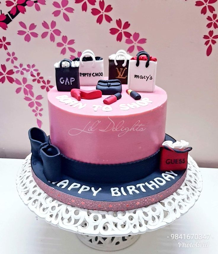 a pink birthday cake with shopping bags on top