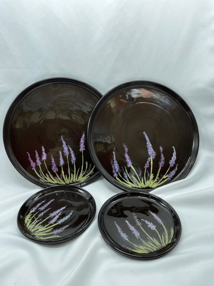 three black plates with purple flowers painted on them