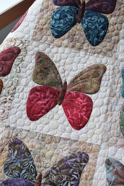 a close up of a quilt with many butterflies on the front and back of it