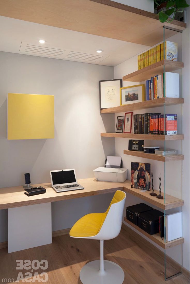 a laptop computer sitting on top of a desk next to a book shelf filled with books