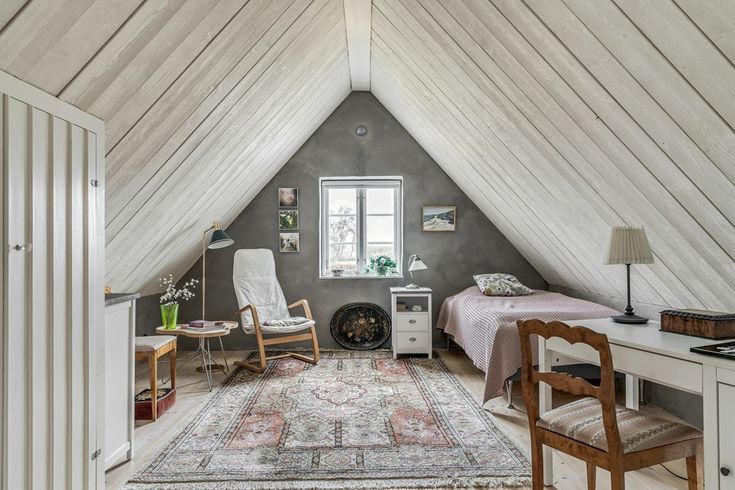 an attic bedroom with two beds and a desk in the corner, along with a rug on the floor