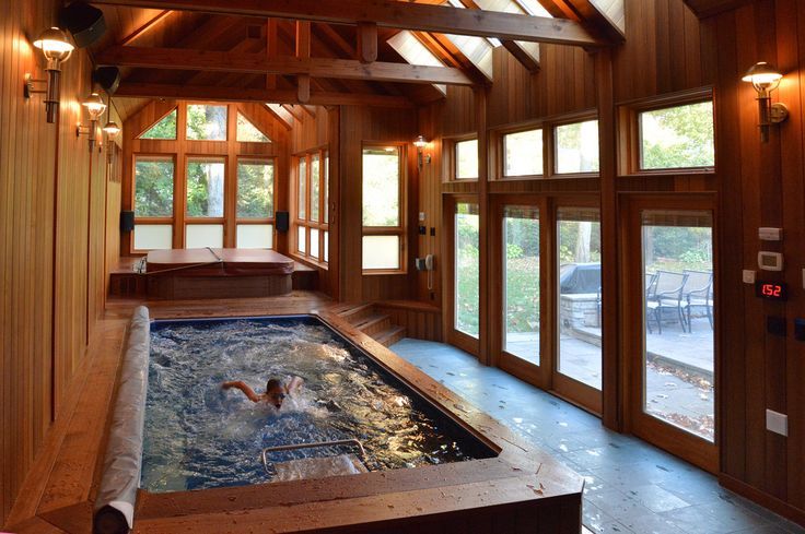 an indoor hot tub in the middle of a room with wood paneling and windows