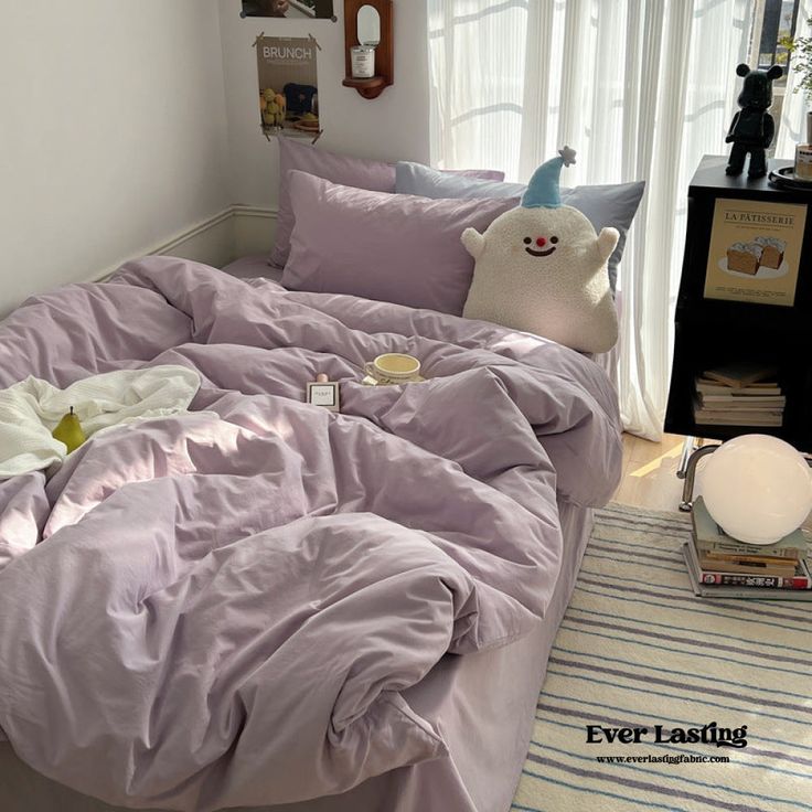 an unmade bed in a bedroom with purple sheets and pillows on top of it