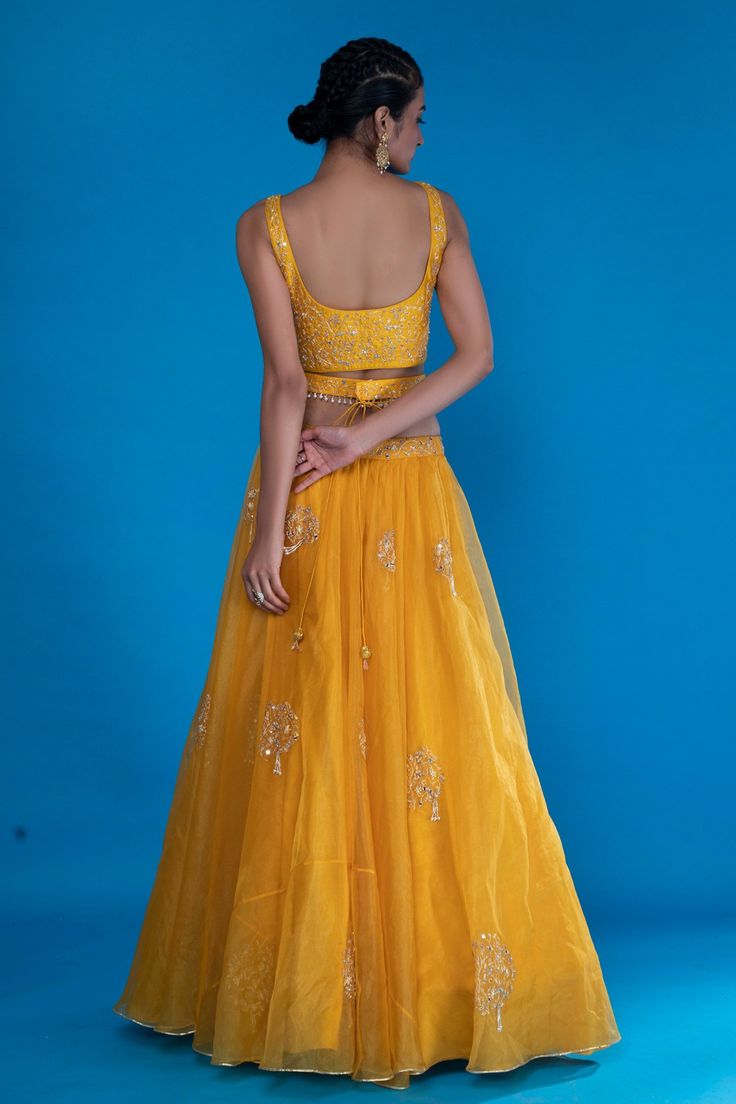 Mustard yellow lehenga in organza base fabric. Paired with a silk blouse with floral motif embroidery and organza dupatta with cutwork hem. Comes with tassel embellished belt.
Components:4
Pattern:Embroidered
Type of Work:Floral Motif
Neckline:V-Neck
Sleeve Length:Sleeveless
Fabric:Lehenga and Dupatta: Organza; Blouse: Silk
Color:Yellow
Other Details:
Floral motif embroidery
Cutwork hem dupatta
Side tassel tie-up lehenga
Tassel embellished belt
Occasion:Wedding, Destination Wedding, Mehendi and Mustard Yellow Lehenga, Wedding Mehendi, Motif Embroidery, Yellow Lehenga, Organza Blouse, Embellished Belt, Blouse Silk, Embroidered Lehenga, Organza Dupatta