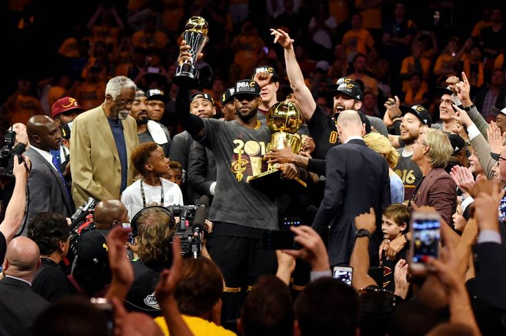 a group of people standing next to each other in front of a crowd holding up trophies