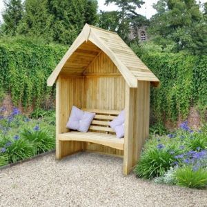 a wooden bench in the middle of a garden with purple flowers and bushes around it