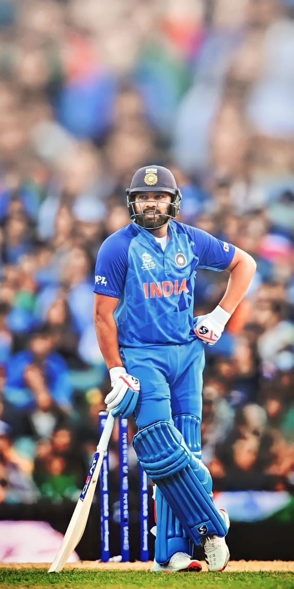 a man standing on top of a cricket field holding a bat and wearing a helmet