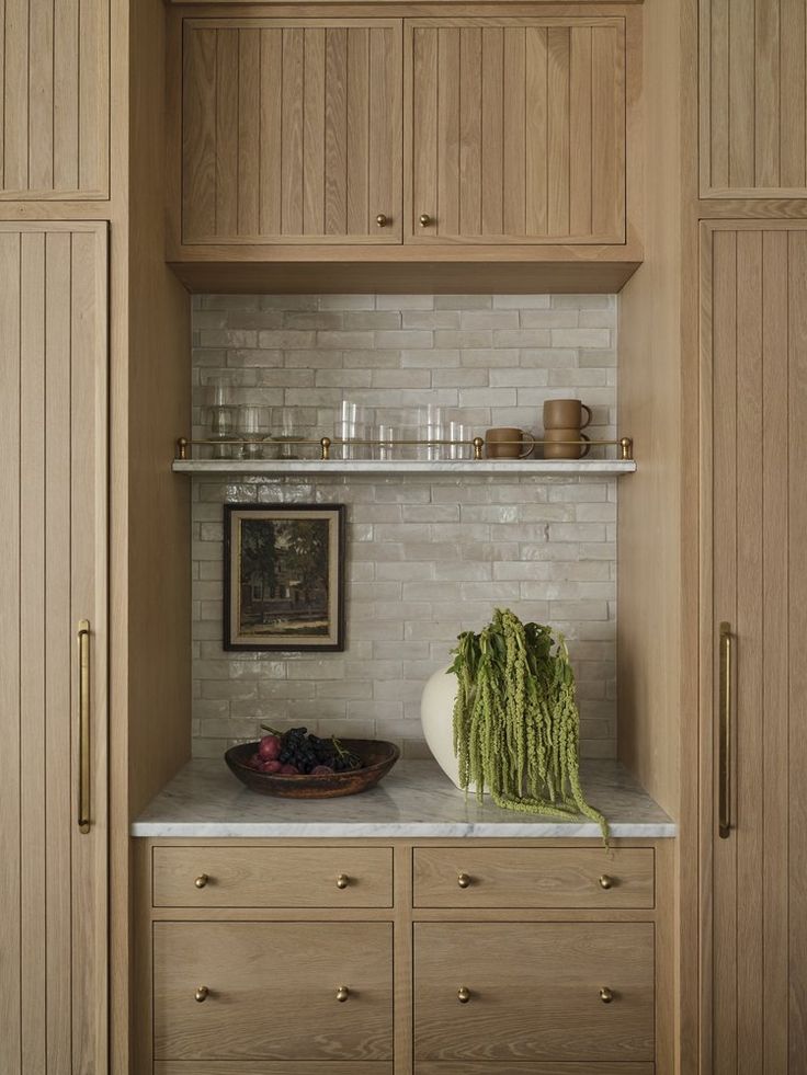 a kitchen with wooden cabinets and white marble counter tops, along with an assortment of vegetables