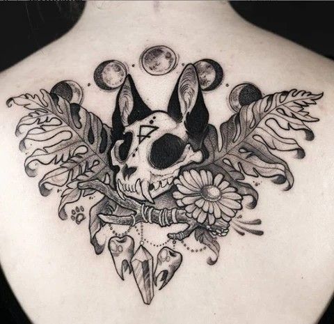 the back of a woman's neck with an animal skull and flowers