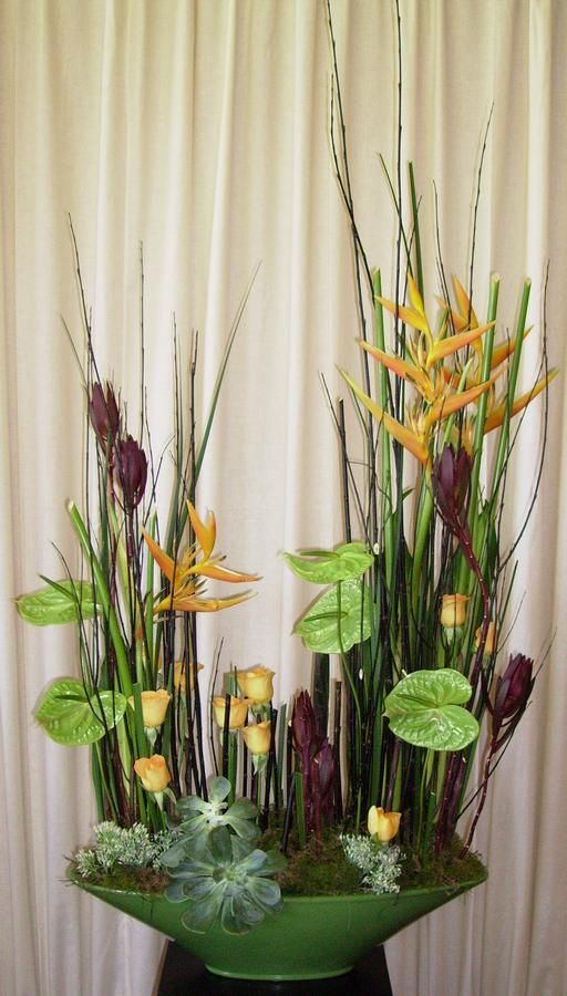 an arrangement of flowers and plants in a green vase