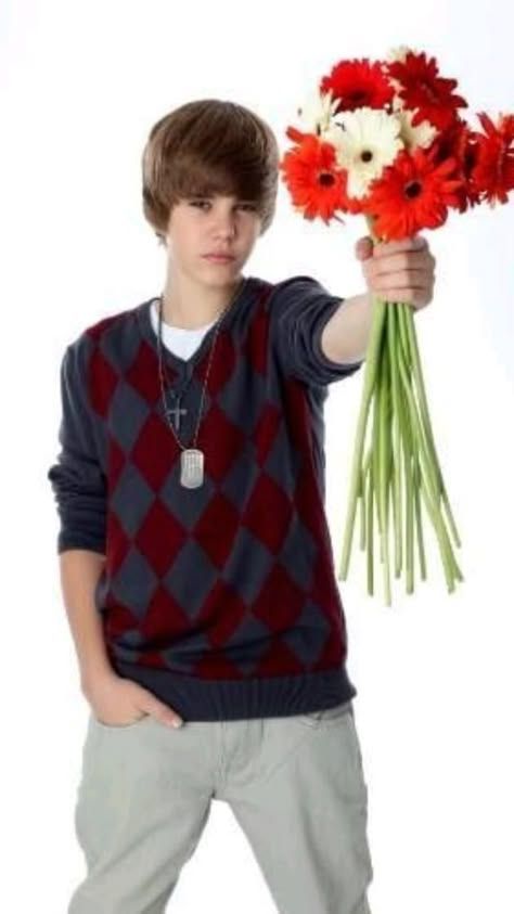 a young man holding flowers in his hand