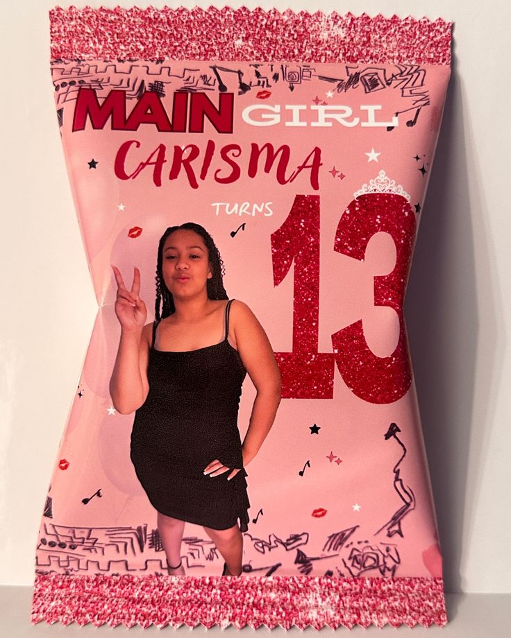 a woman in a black dress standing next to a pink pillow with the number 13 on it