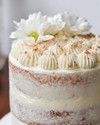 a close up of a cake with white frosting and flowers on the top layer