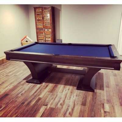 a pool table in a room with hard wood flooring and white walls on the wall