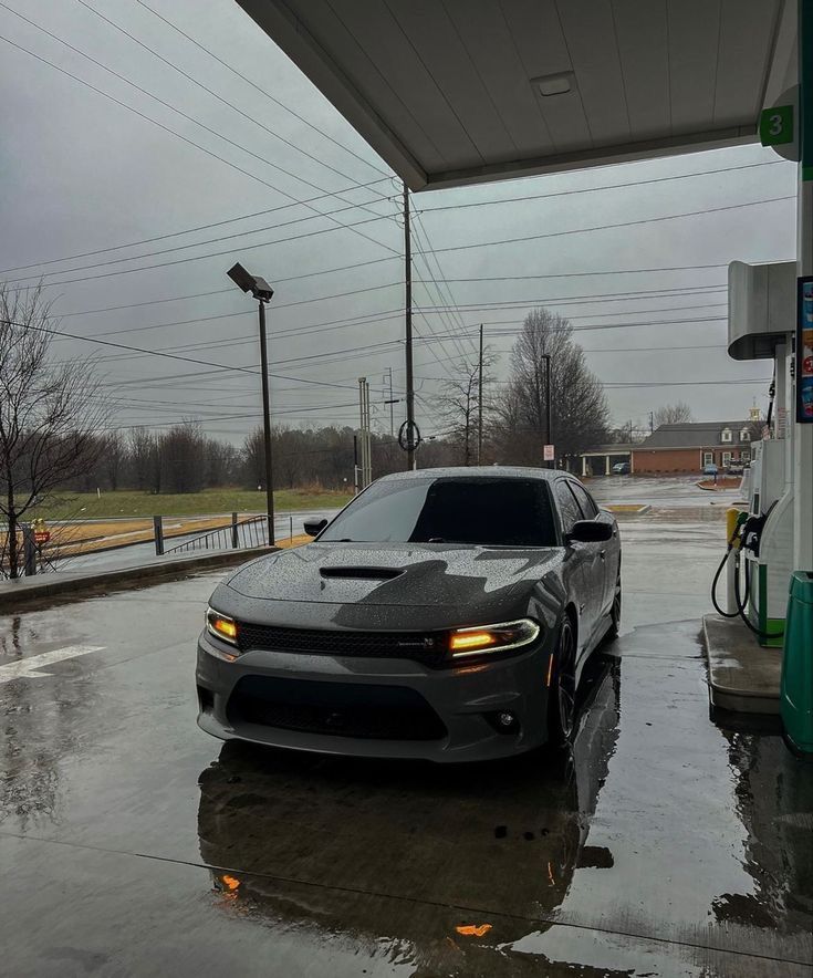 a car is parked at a gas station in the rain