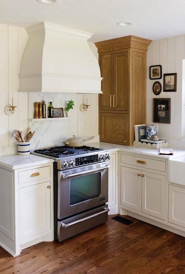 a stove top oven sitting inside of a kitchen next to white cabinets and wooden floors