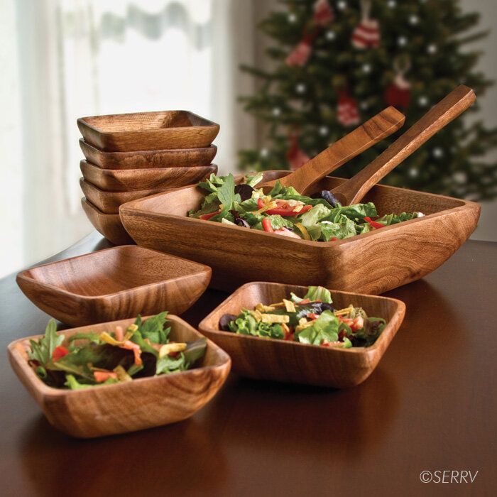 wooden bowls filled with salad sitting on top of a table next to a christmas tree