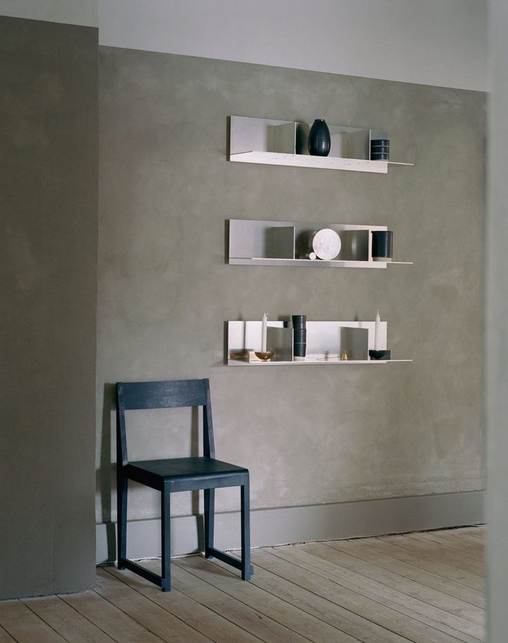 a chair sitting in front of a wall with shelves on each side and plates on the top shelf