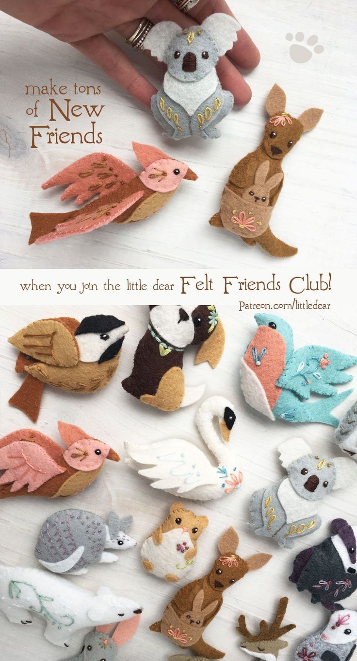 there are many small felt animals on the white table and in front of them is a hand holding one