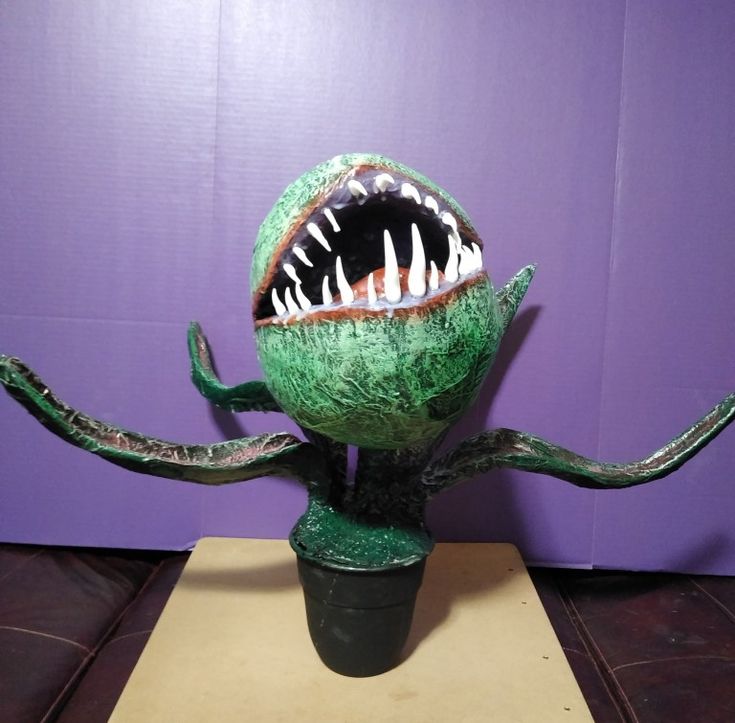 a green vase with an open mouth and sharp teeth