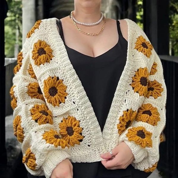 a woman wearing a white and yellow crochet cardigan with sunflowers on it