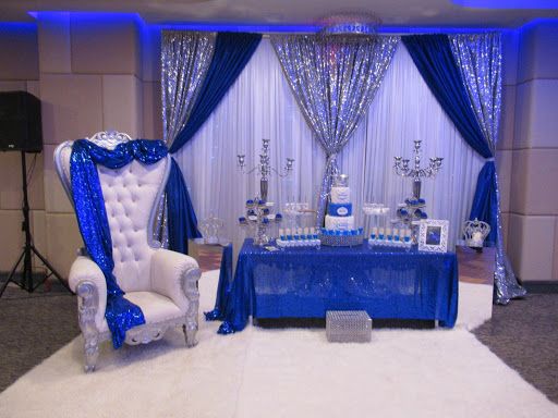 a blue and white wedding set up with an elegant chair, crystal vases and candles