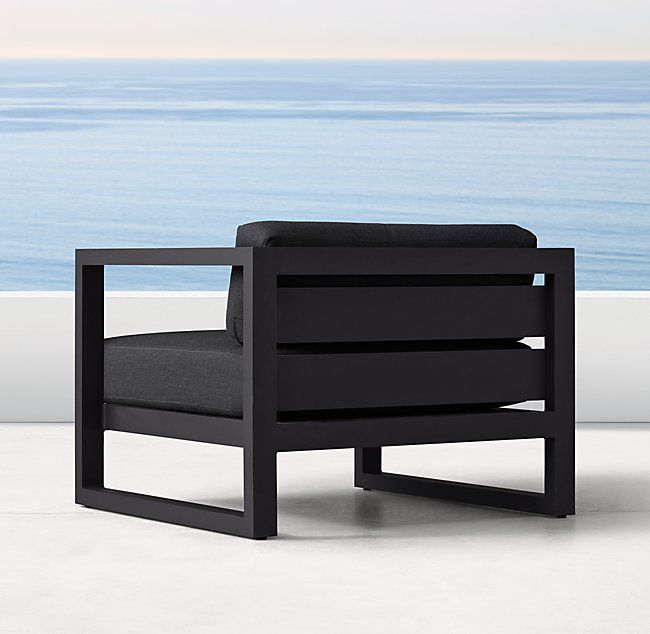 a black chair sitting on top of a white floor next to an ocean side wall