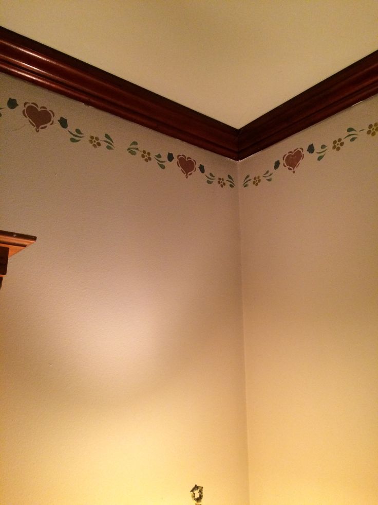 a bathroom with a toilet and sink in it's corner, next to a wall decorated with flowers