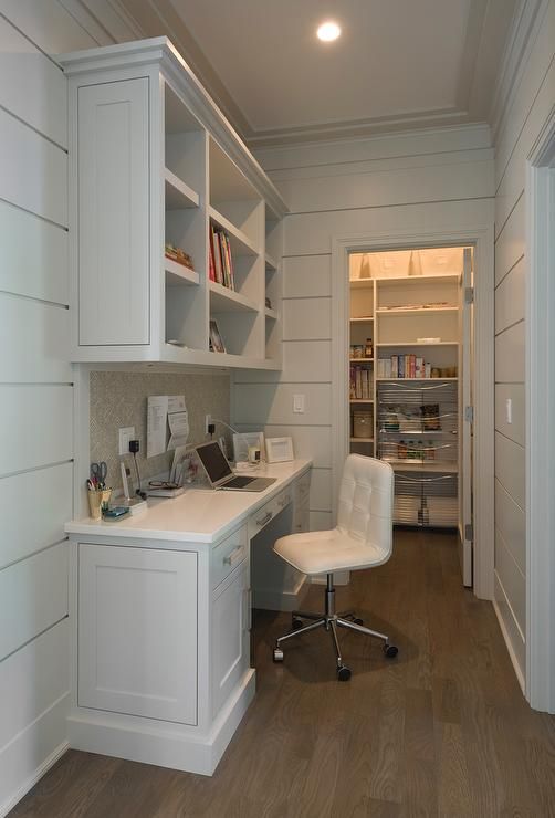 a white desk and chair in a room with wood flooring on the walls, along with built - in bookshelves