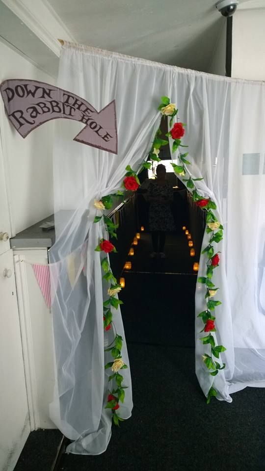 an open doorway with white curtains and flowers on the door, in front of a black carpeted floor