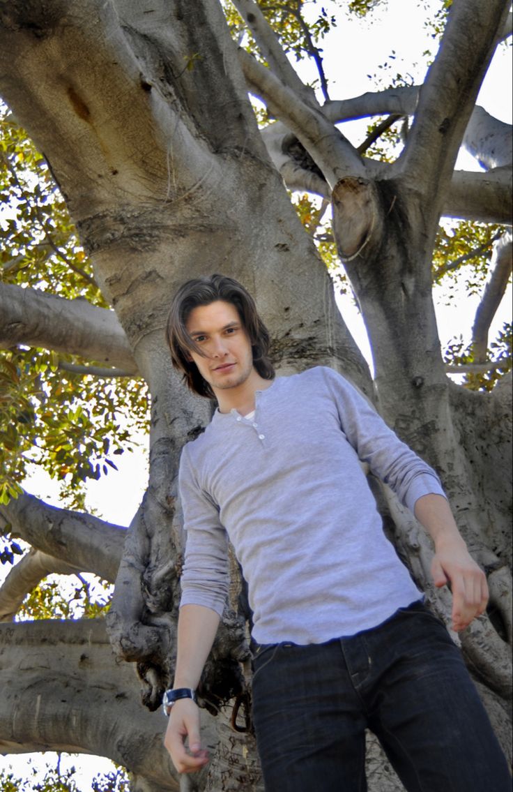 a young man standing in front of a tree