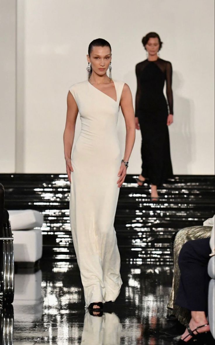 a woman walking down a runway in a white dress