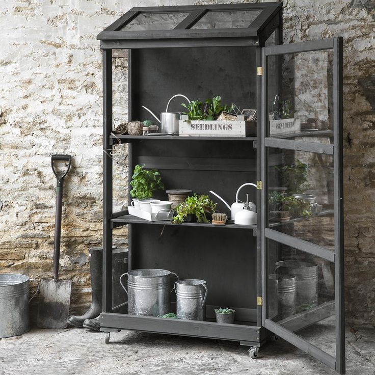 a shelf filled with potted plants next to a brick wall