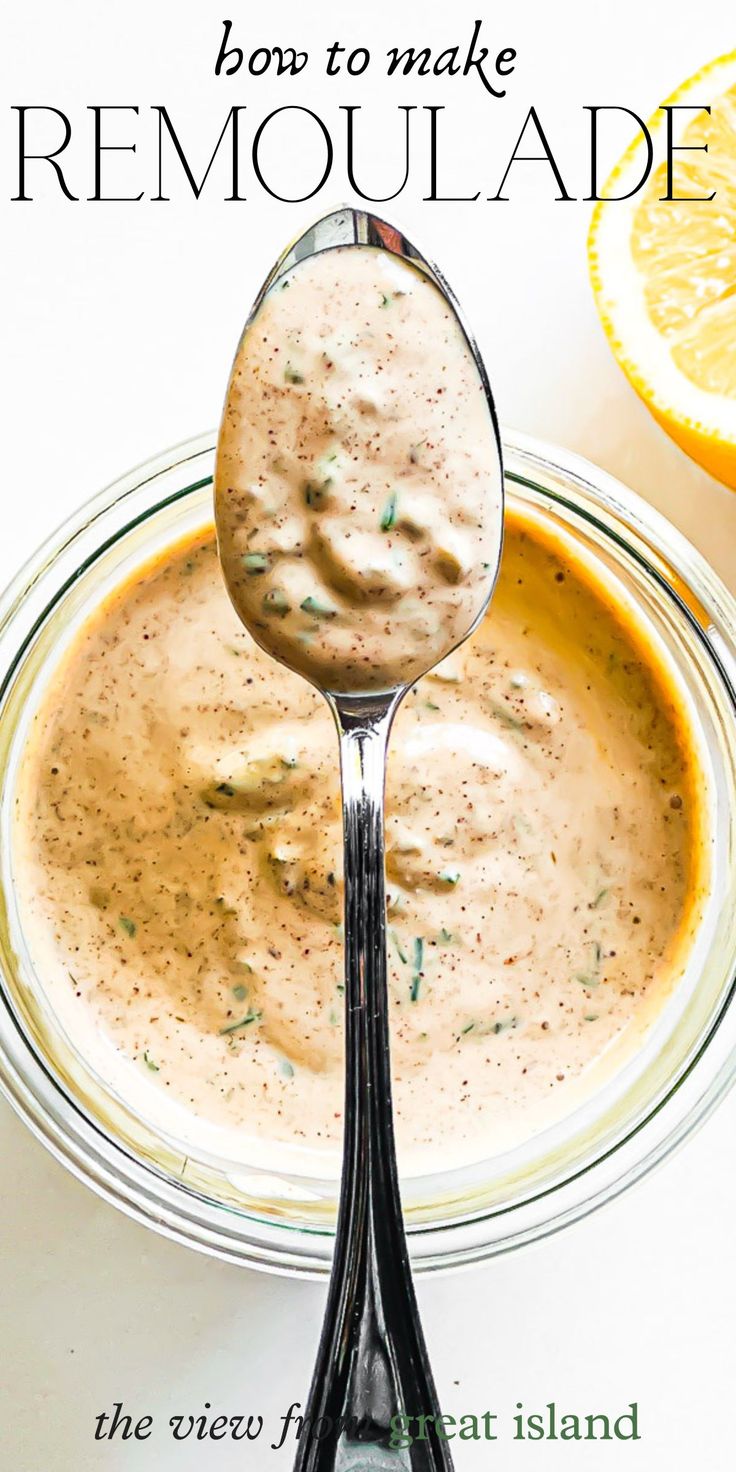 a spoon full of homemade remoulade in a glass bowl with an orange slice on the side