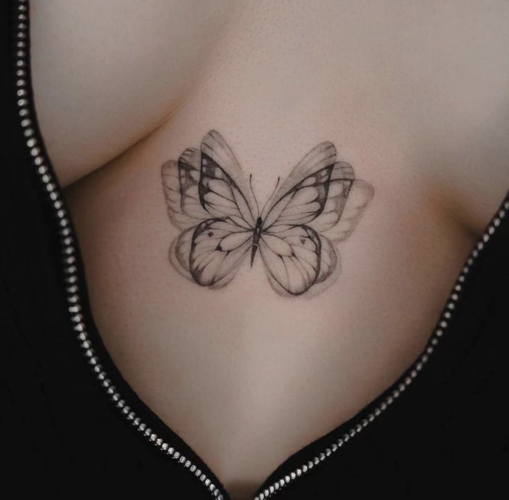 a black and white butterfly tattoo on the back of a woman's chest,