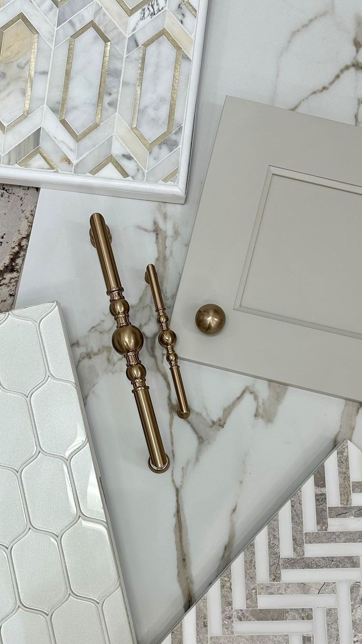 marble counter top with gold handles and decorative tiles on it, including a white cabinet door