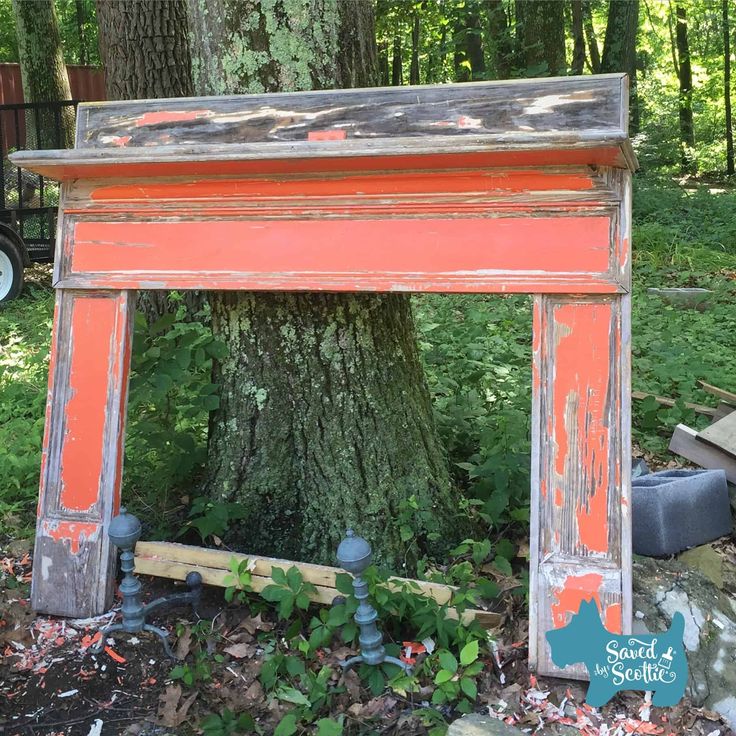 an old wooden frame sitting in the middle of a forest next to a large tree