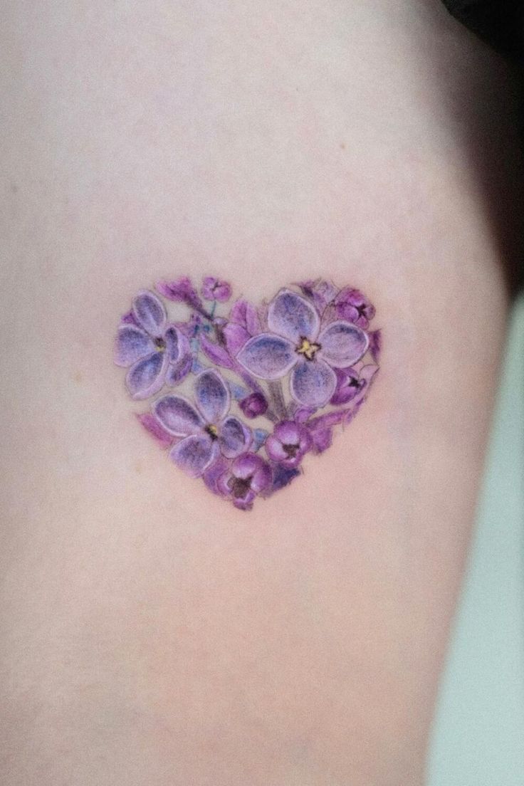 a heart shaped tattoo with purple flowers on the back of her left shoulder and chest