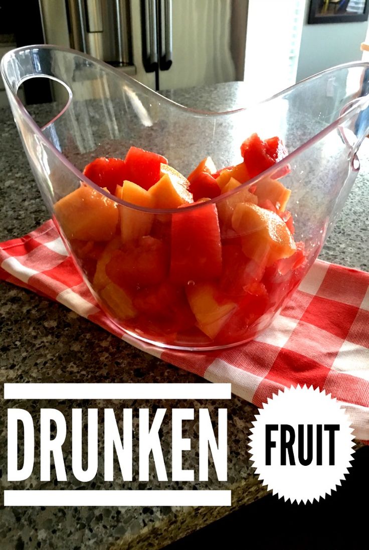 a glass bowl filled with fruit sitting on top of a counter next to a red and white checkered napkin