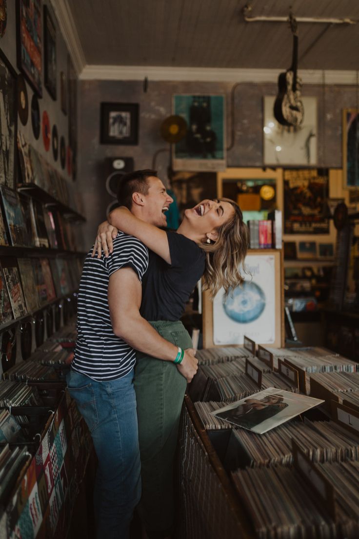 a man and woman are hugging in a record store with records on the shelves behind them