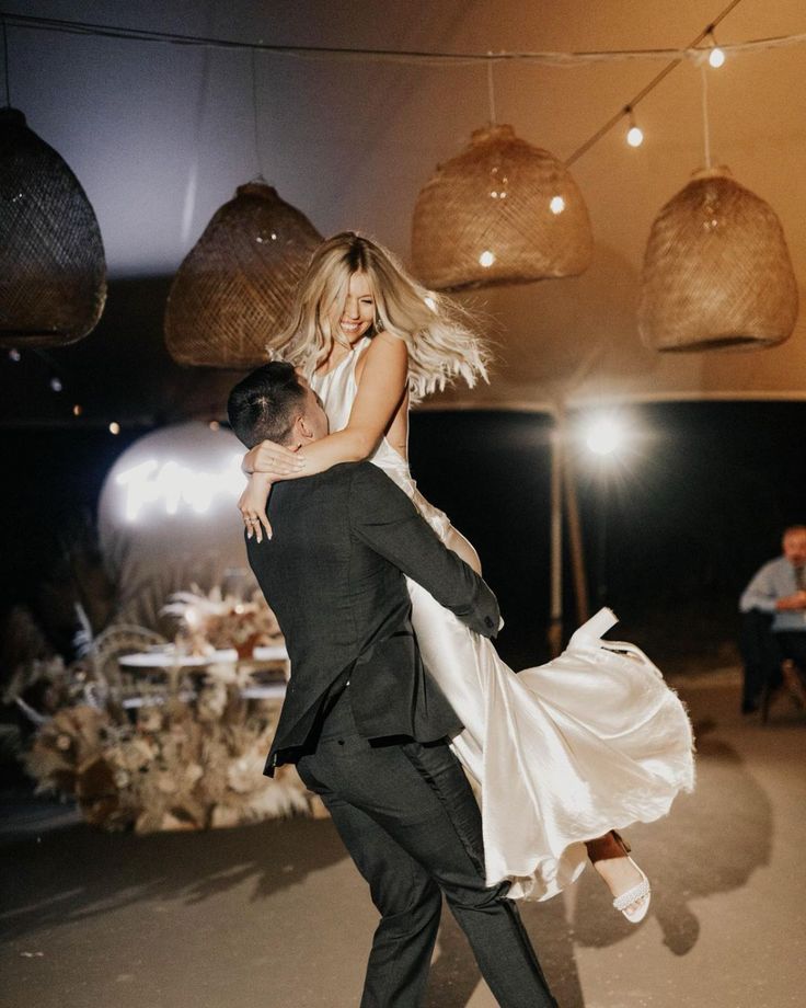 a man and woman dance together in an indoor area with lights hanging from the ceiling