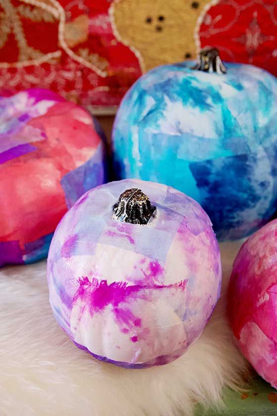 four painted balls sitting next to each other on a white fur covered surface with teddy bears in the background